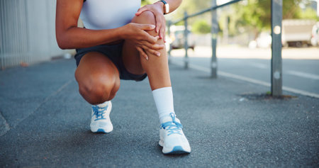 Person, knee pain or exercise injury in city, muscle cramps or tension with fitness mistake. Fibromyalgia, discomfort and female athlete hands with tendon tear, sport fracture or inflammation outdoorの写真素材
