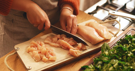 Hands, chicken and cutting board in kitchen, home and meal prep with knife, poultry and cooking healthy food. Person, chef and tools for organic meat, nutrition and diet for wellness at apartmentの写真素材