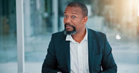 Confused, employee and mature man in office, surprised and listening to bad news, corporate and job loss. Business, fired and black person with shock, thinking and termination for poor performanceの写真素材