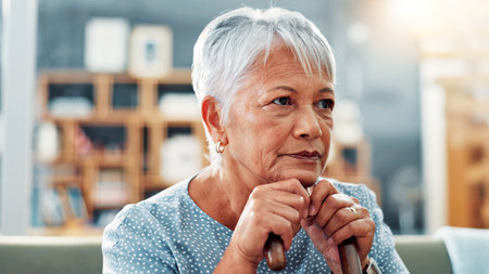 Old woman, thinking or regret on sofa in house for nostalgia, past or history with lonely pensioner in retirement. Mistake, reflection or memory with grief, loss or contemplating life in nursing homeの写真素材