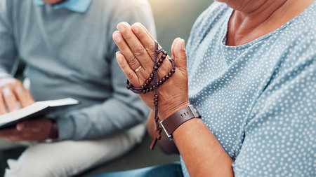 Hands, rosary and couple religion with bible in home to worship Jesus Christ, spiritual faith and crucifix meditation. Old people, prayer and holy necklace on sofa with scripture guidance and praiseの写真素材