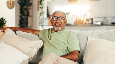 Happy, relax and portrait of senior man on sofa in home with calm, peace and retirement. Smile, glasses and elderly male person from Brazil in living room with health and wellness in apartment.の写真素材