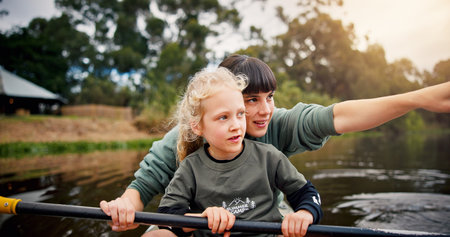 River, child and woman with pointing for kayak, water activity and adventure in summer camp. Lake, female instructor and girl with learning for canoeing, skills development and paddle outdoor in boatの写真素材