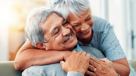 Bonding, hug and senior couple in home, smile and commitment for relationship, love and relax in lounge. House, old man and care for woman in living room, embrace and retirement for elderly peopleの写真素材