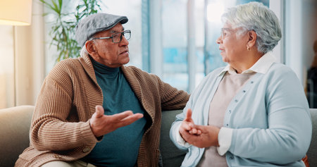 Senior couple, argument and sofa at house for fighting, divorce conflict and partner disagreement. Elderly people, communication problem and confront of separation, marriage crisis and betrayal dramaの写真素材