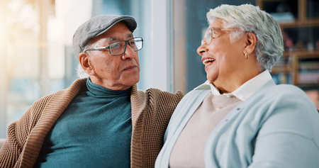 Senior couple, relax and love in home with smile, bonding and healthy relationship in retirement. Elderly man, mature wife and laugh in living room with commitment, trust and support in marriageの写真素材
