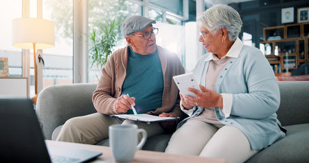 Senior couple, calculator and paperwork on sofa with finance, budget and review for bills in...