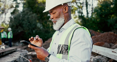 Building, development and phone with construction worker black man on site for communication or planning. Architecture, app and hardhat with mature developer outdoor for engineering or excavationの写真素材