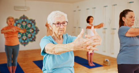 Yoga studio, senior women and fitness with instructor, spiritual wellness and pilates. Elderly people, trainer and group in health club, balance and coach with exercise, retirement and stretchingの写真素材