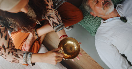 Tibetan bowl, relax and hands of person in studio for wellness retreat, healing and meditation. Chakra balance, peace and sound therapy with above of shaman for energy, holistic ritual and harmonyの写真素材