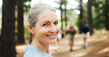 Hiking, nature and portrait of mature woman with smile for exercise, workout and walking for wellness. Fitness, travel and person in forest and woods for trekking, adventure and journey outdoorの写真素材