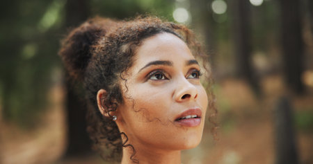 Hiking, thinking and woman in woods, wellness and thoughtful with reflection. Person, outdoor and hiker with break, nature and countryside with healthy, daydreaming and explore with journey and calmの写真素材