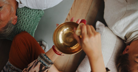 Tibetan bowl, healing and hands of person in studio for wellness retreat, relax and meditation. Chakra balance, peace and sound therapy with above of shaman for energy, holistic ritual and closeupの写真素材