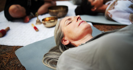 Woman, sound and meditation with tibetan bowl for spiritual healing or alternative medicine in nature. Female person, sleeping or lying with guru for stress relief, mindfulness or holistic cultureの写真素材