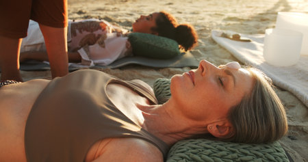 Women, crystal and energy at beach with chakra balance, therapy and healing with rest on vacation. People, stone and holistic care with mineral, mindfulness and shaman with zen on ground in summerの写真素材