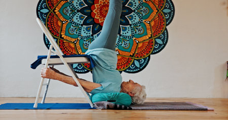 Exercise, upside down or yoga and woman in studio with wall art for fitness or wellness routine. Balance, pilates or profile and senior person in class with mandala symbol for holistic healthの写真素材