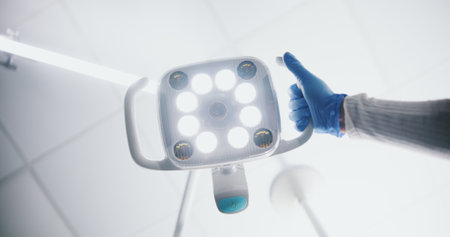 Bright, theatre and hand with surgical light, medical or intense illumination for surgeon or operation. Hospital, health and person with gloves for safety, PPE or expert with equipment for visibilityの写真素材