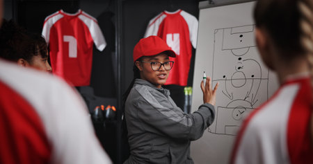 Women, coach and soccer team with whiteboard for game plan, match or player formation in locker room. Female people, coordinator or teaching with presentation or meeting for sport strategy togetherの写真素材
