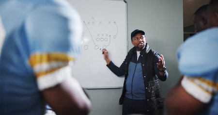 Whiteboard, team and man with football strategy in locker room for game plan or defense formation. Touchdown tactics, sports coaching and manager with people, match feedback and training analysisの写真素材