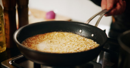Cooking, pan or risotto with hand in kitchen of restaurant closeup for diet, health or nutrition. Gas stove, ingredients and rice with chef person in hotel for gourmet cuisine, hospitality or serviceの写真素材