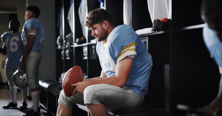 Thinking, football player and sports with ball in locker room for preparation, match and game plan. Athlete, man and waiting for half time of competition strategy, fitness challenge and tournamentの写真素材