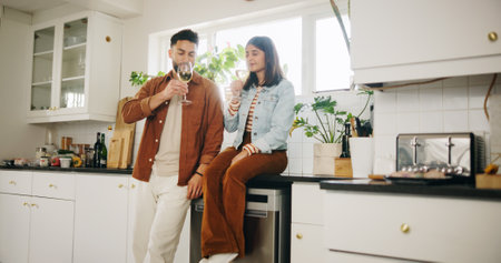 Kitchen, couple and glasses of wine for celebration, smell and anniversary in healthy relationship. Home, man and woman with alcohol beverage for date, commitment and bonding with drink in marriageの写真素材