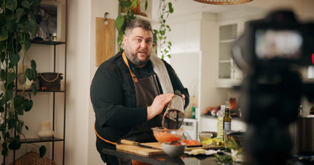 Ingredients, cooking and man with live streaming in kitchen for dinner recipe, meal prep or video recording. Culinary influencer, content creation or person with cuisine tutorial or nutrition in homeの写真素材