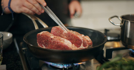 Cooking, stove and chef with meat in pan in kitchen for culinary skill, recipe and meal prep for dinner. Food, sear and person with beef, steak and protein for gourmet dish, ingredients and cuisineの写真素材