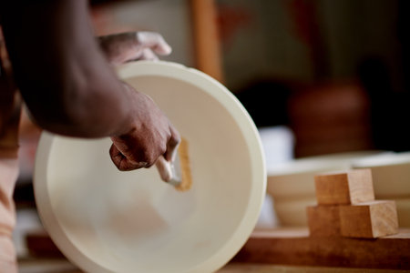 Paint brush, pottery and hands of person in workshop with creativity, art or craft process. Design, hobby and ceramist with clay piece for ceramic sculpture with pattern, production or small businessの写真素材