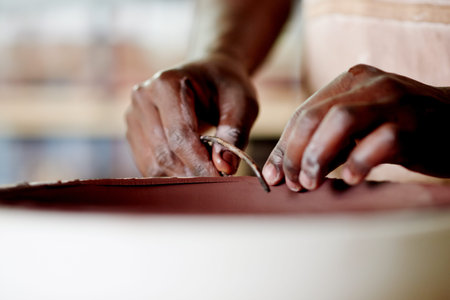 Hands, clay and pottery with tools at workshop for ceramic manufacturing, craft or process for sculpture. Person, art or equipment for shape, patterns or results with creativity for texture at studioの写真素材