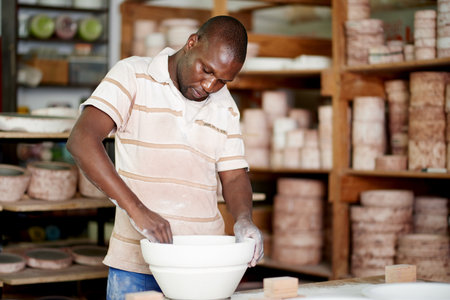 Pottery, workshop and black man at ceramic store for creative, art or manufacturing product. Retail, mold and African male person with mud sculpture at startup small business with texture skill.の写真素材