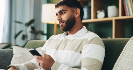 Home, man and sad with thinking for smartphone, online message and breakup with contact on sofa. House, male person and broken heart with tech for bad news, social media and rejection on dating appの写真素材