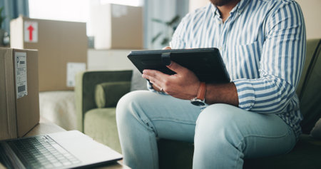 Home, hands and typing on tablet for logistics, distribution and remote work for customer service. Sofa, person and business owner with technology for ecommerce, inventory management and supply chainの写真素材