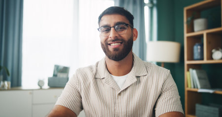 Portrait, glasses and happy man in apartment for relax, peace or calm on weekend break in home. Smile, living room and male person with spectacles for vision, resting and chill with confidence in UAEの写真素材