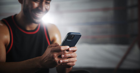 Hands, phone and texting at gym by boxing ring with notification for invite to global contest at...