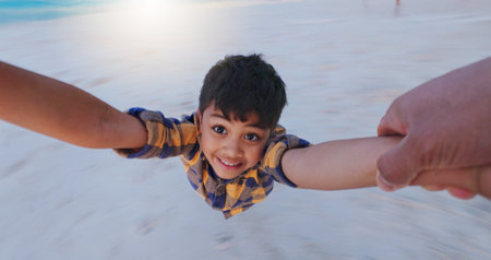 Boy, pov and parent with spin at beach with smile, portrait and holding hands for bonding on vacation. Child, swing and happy with games, care and playful with love by ocean on holiday in Mexicoの写真素材