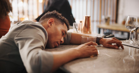 Man, drunk and sleeping on bar counter for alcohol abuse, addiction or intoxication at restaurant. Male person, asleep or customer lying with drink in fatigue for alcoholism or hangover on tableの写真素材