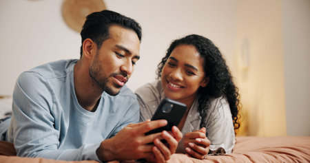 Happy couple, relax or browsing with phone on bed for online entertainment, humor or comedy at home....