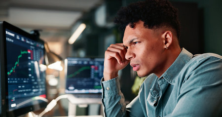 Man, trading and computer screen with stress for graphs with market crash, results and stock value at office. Person, frustrated and investor at night for stats, worry and lost revenue at agencyの写真素材