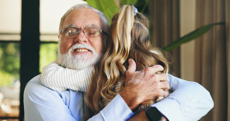 Hug, grandchild and grandpa with smile, home and love for granddaughter in living room, family and care. Happy, elderly man and bonding with girl in lounge, embrace and excited for visit in houseの写真素材