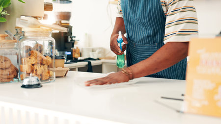 Hands, cleaning countertop and man in cafe, spray bottle and disinfectant with maintenance. Closeup,...
