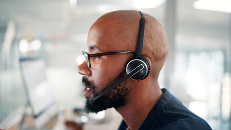 Office, call center and black man with headset on computer for contact us, crm service and customer support. Business, consultant and profile of person talking for communication, advice and feedbackの写真素材