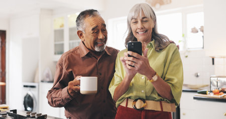 Happy, phone and mature couple in kitchen in home reading online news for political update. Coffee, smile and man with woman for mobile app on cellphone for blog post with bonding in morning at houseの写真素材