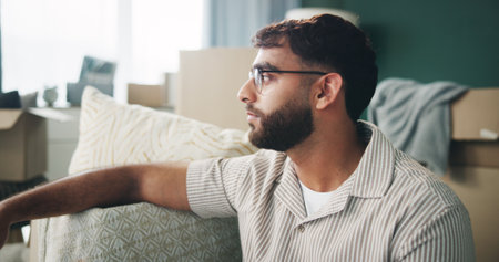Home, man and boxes with stress for thinking, contemplation and serious with packing for eviction. Apartment, male person and sad with thoughts for relocation, rent and moving out in living roomの写真素材