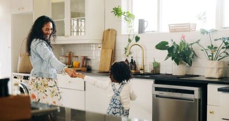 Dancing, mother and girl in kitchen, home and bonding together with happiness, support and energy. Family, parent and mama with daughter, movement and child development with love, celebration or careの写真素材