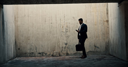 Business, phone and space with man by concrete wall for communication or networking. Application, social media or text message and person with briefcase on mockup for data, information or updateの写真素材