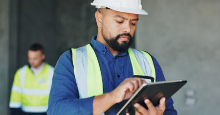 Building, serious and tablet with construction worker man on site for civil engineering or development. App, inspection and planning with developer person on worksite as project management supervisorの写真素材