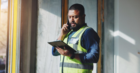 Building, phone call and tablet with construction worker man on site for civil engineering or development. App, conversation and planning with developer person on location for project managementの写真素材