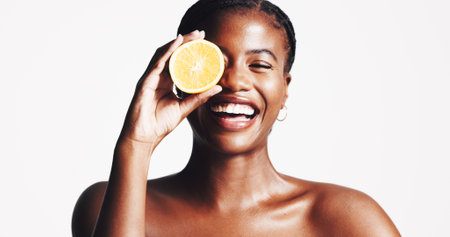 Happy, black woman and portrait with lemon for skincare, detox or vitamin C on a white studio background. Female person, model or smile with citrus fruit for natural organic treatment on mockup spaceの写真素材