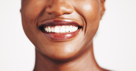 Smile, woman and closeup of mouth in studio for teeth whitening, dental hygiene and oral care. Happy, female person and implant for veneers, fresh breathe and cleaning results on white backgroundの写真素材